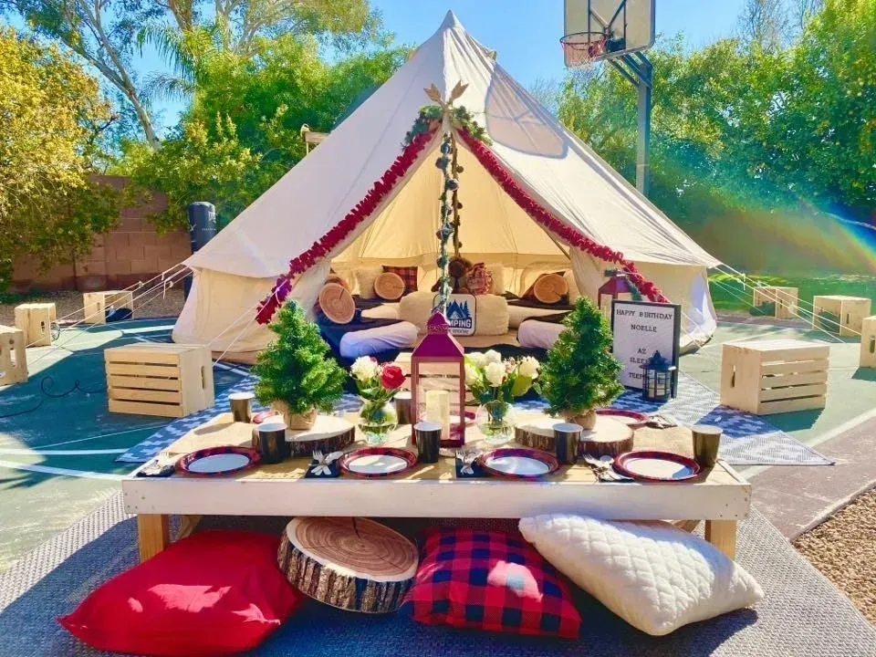 A tent with a table and pillows in front of it.