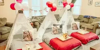 A living room decorated for a sleepover with teepees and pillows.