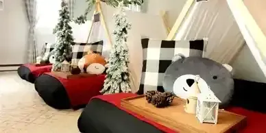 A room decorated for a christmas party with teepees , pillows , lanterns and trees.