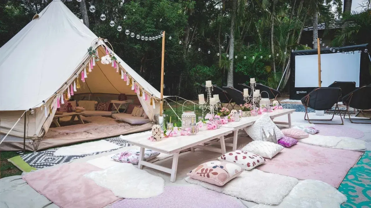 A tent with tables and pillows set up in front of it.
