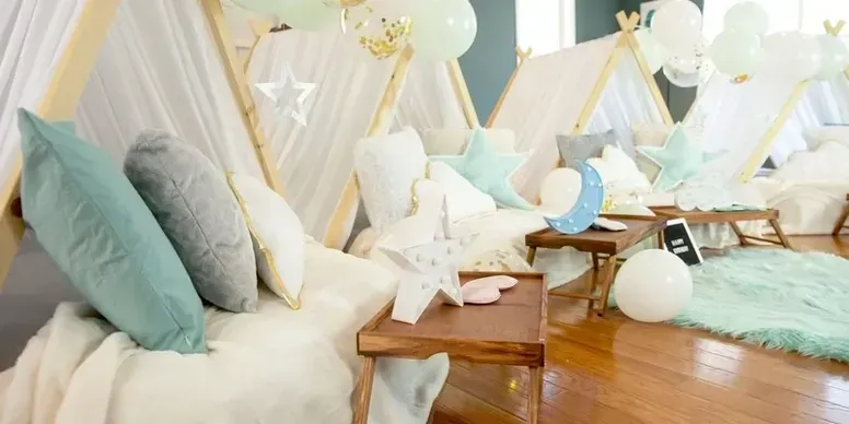 A room filled with beds , pillows , balloons and teepees.