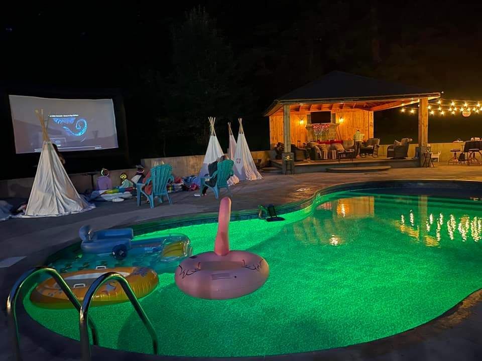 A swimming pool with a flamingo float in it at night.