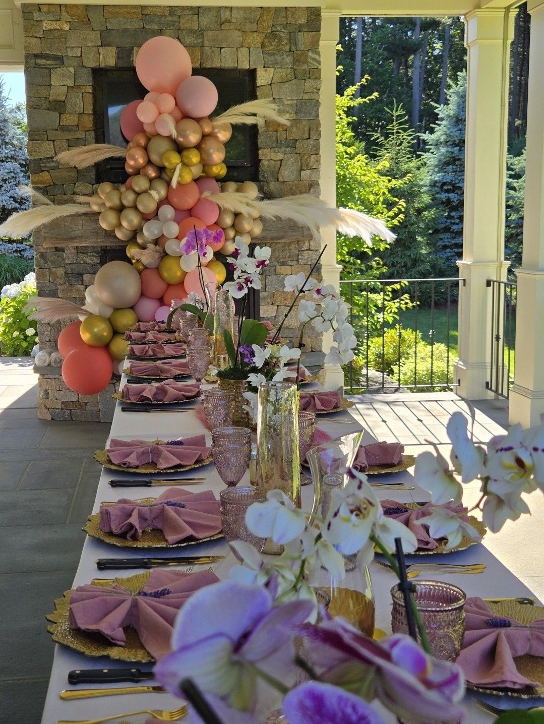 A long table with plates , utensils , flowers and balloons on it.
