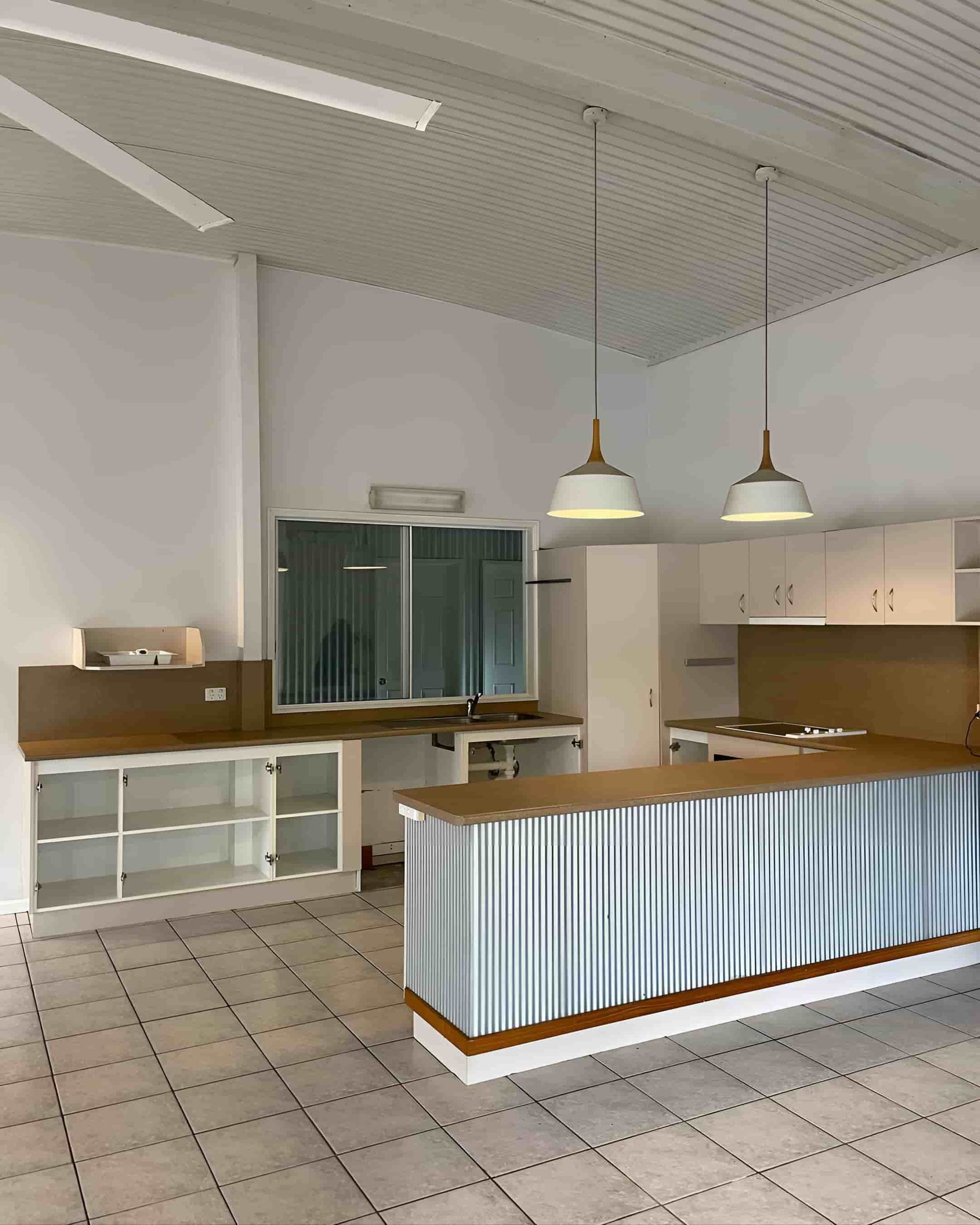 An Empty Kitchen With A Large Metal Island In The Middle — Glittering Cleaning Service In Townsville, QLD