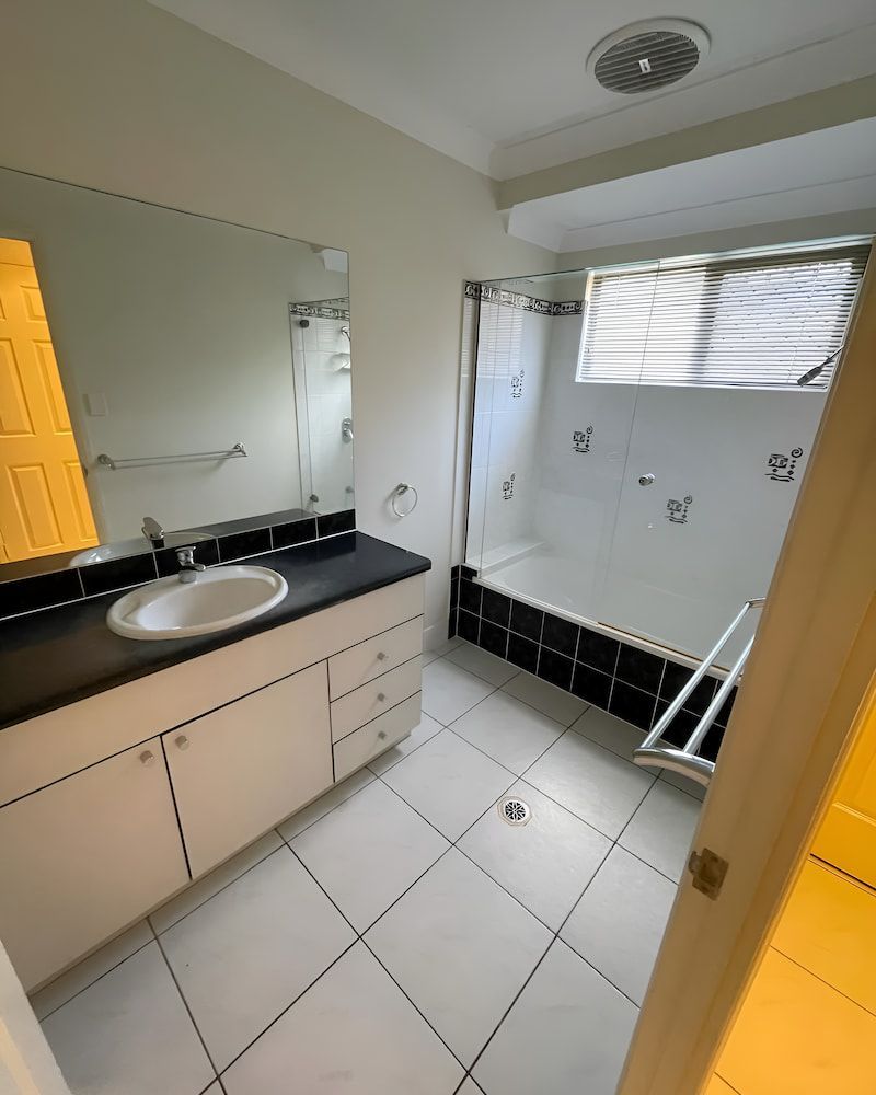A Bathroom With A Sink A Mirror And A Bathtub — Glittering Cleaning Service In Townsville, QLD
