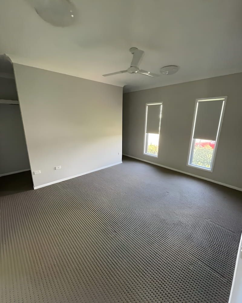 An Empty Living Room With A Ceiling Fan And Two Windows — Glittering Cleaning Service In Townsville, QLD