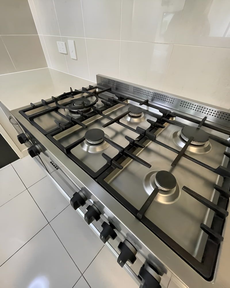 A Stainless Steel Stove Top Oven Is Sitting On A Counter In A Kitchen— Glittering Cleaning Service In Townsville, QLD