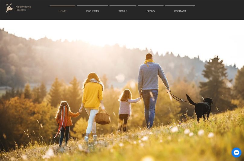 A family is walking a dog on a leash in a field.