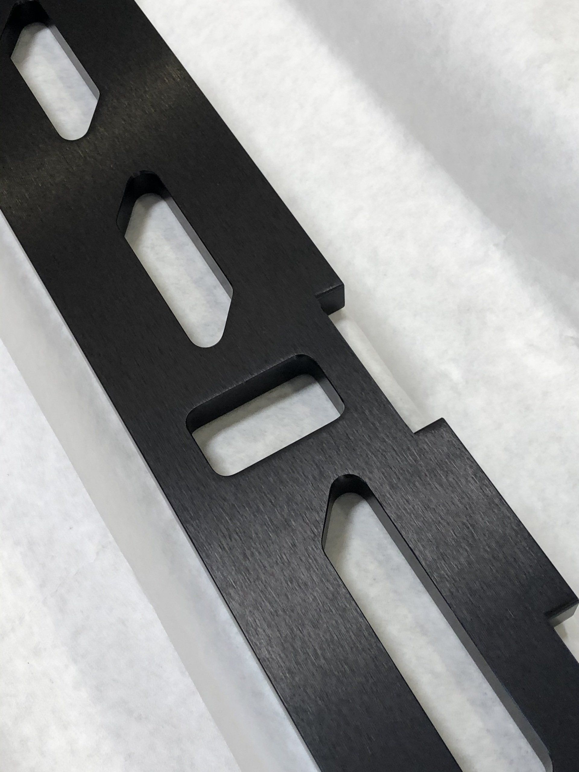 Black metal bracket with elongated holes.