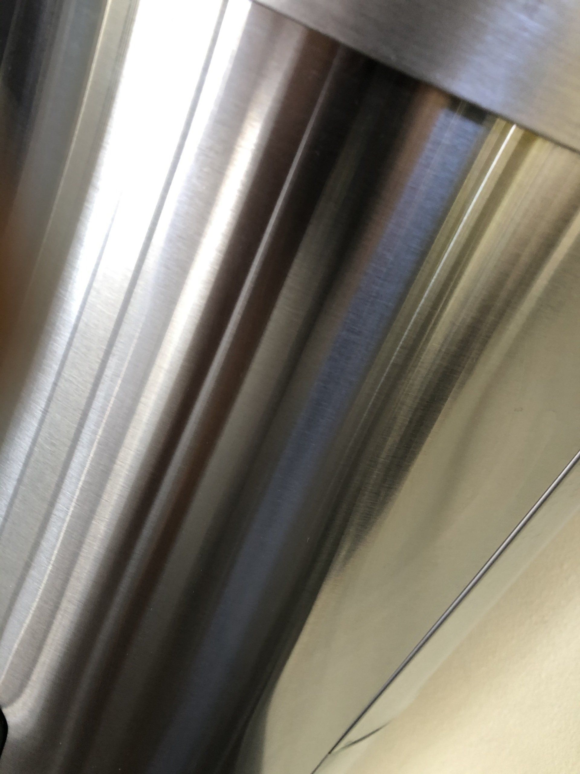 Close-up of a shiny, metallic surface with vertical lines and reflections.