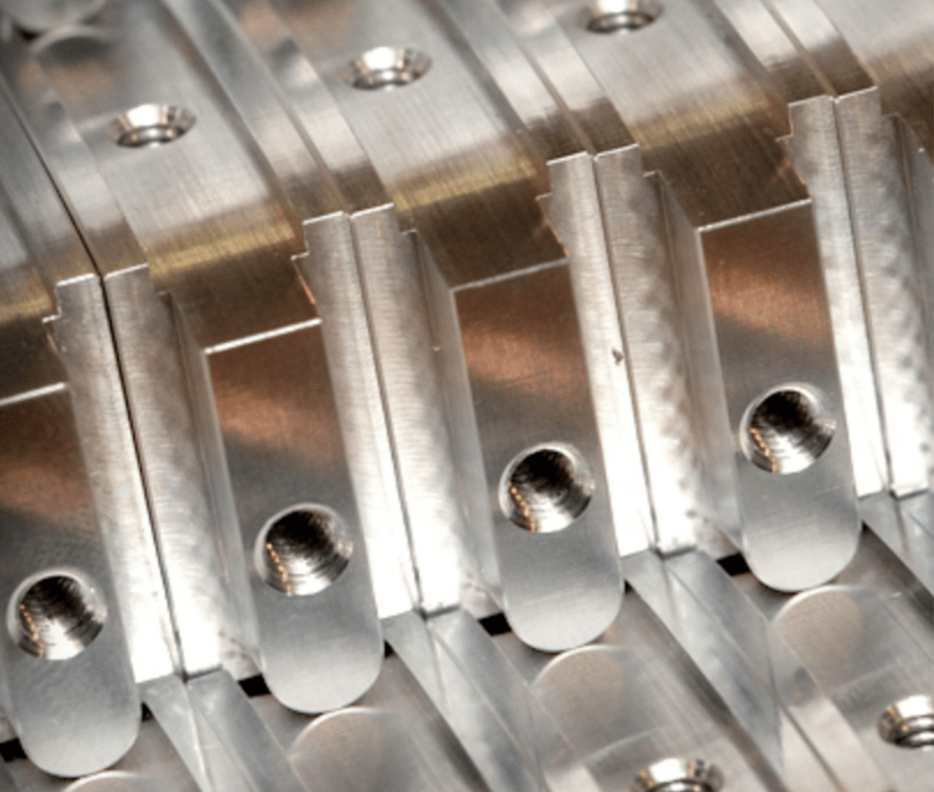 Close-up of aligned, metallic machine parts with screw holes.