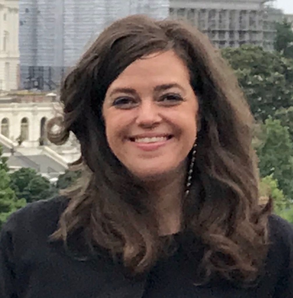 A woman is smiling for the camera in front of a building.