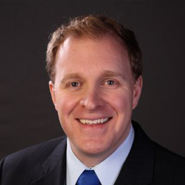 A man in a suit and tie smiles for the camera