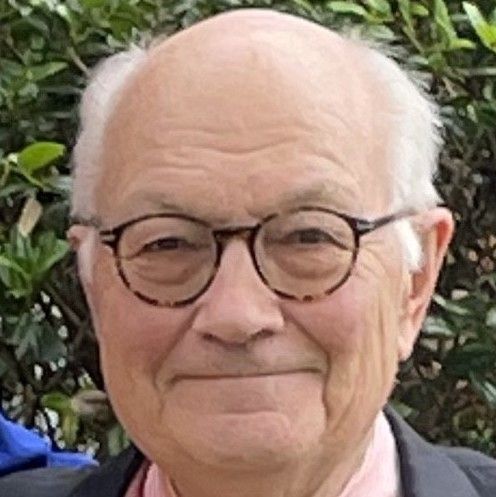 A close up of an older man wearing glasses and a suit.