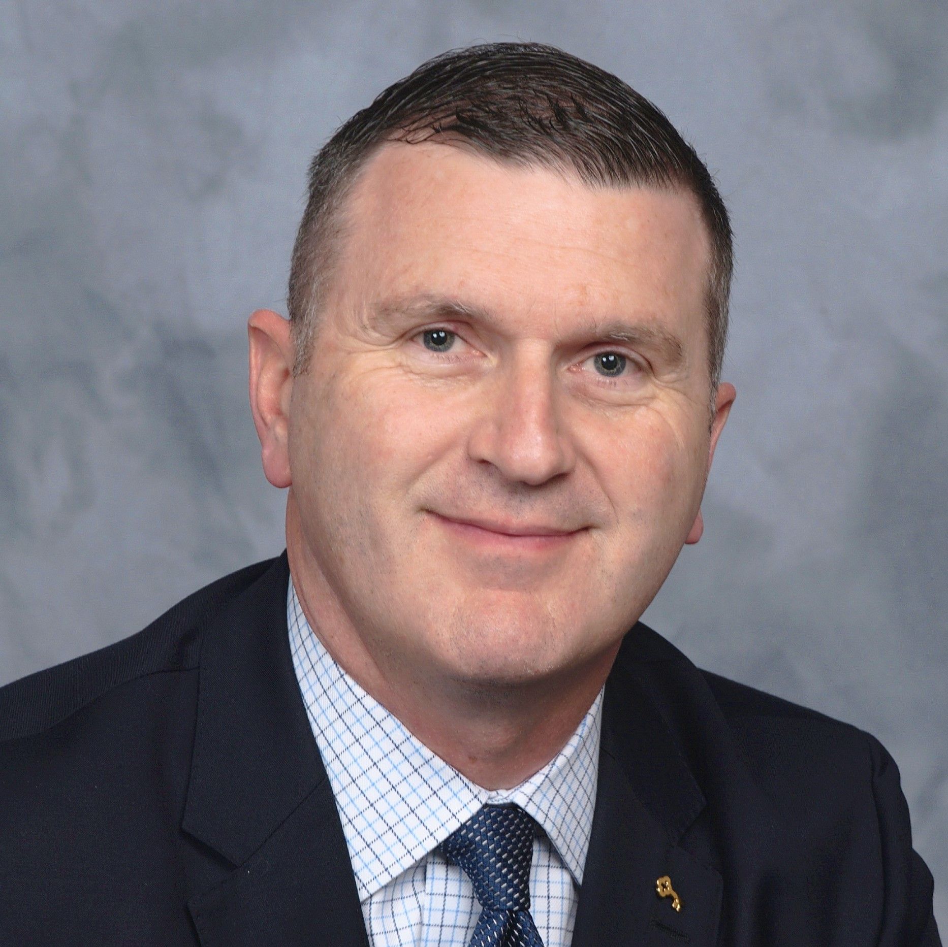 A man in a suit and tie is smiling for the camera