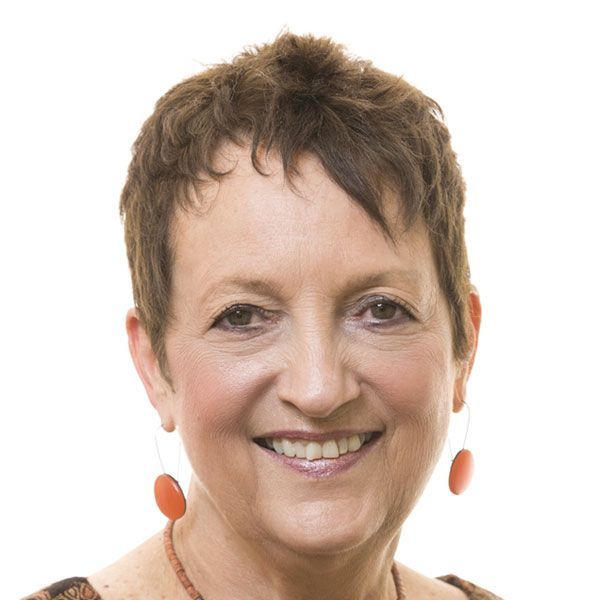 A woman with short hair and earrings smiles for the camera