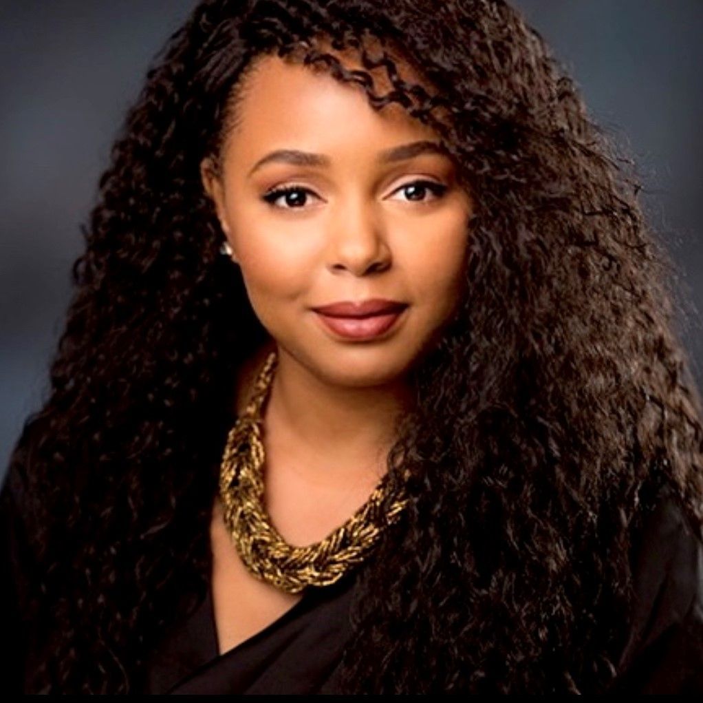 A woman with long curly hair wearing a gold necklace