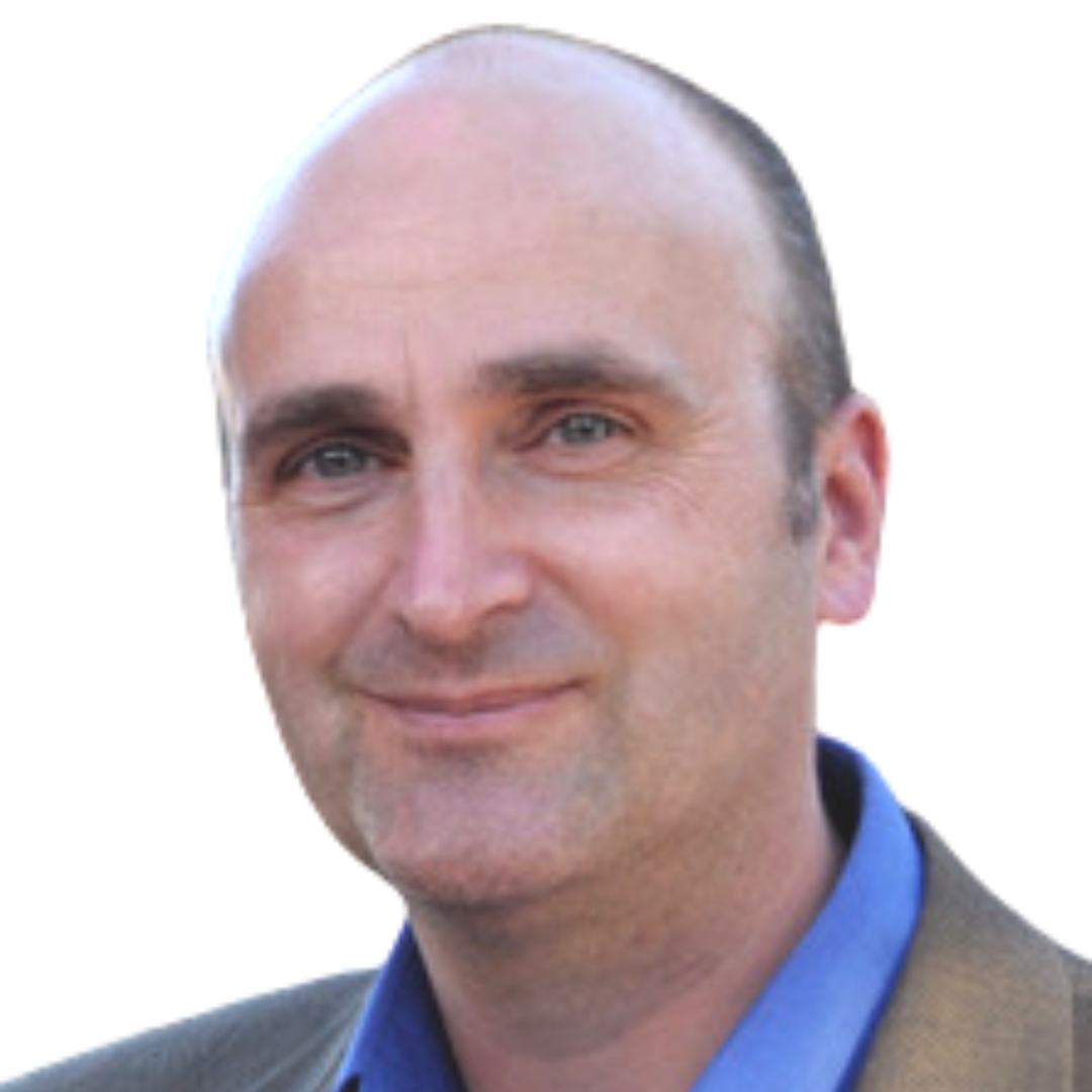 A bald man in a suit and blue shirt smiles for the camera