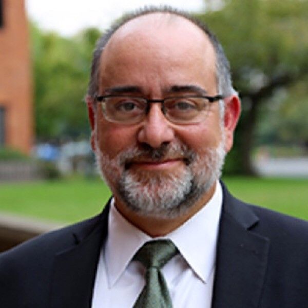 A man with a beard and glasses is wearing a suit and tie.