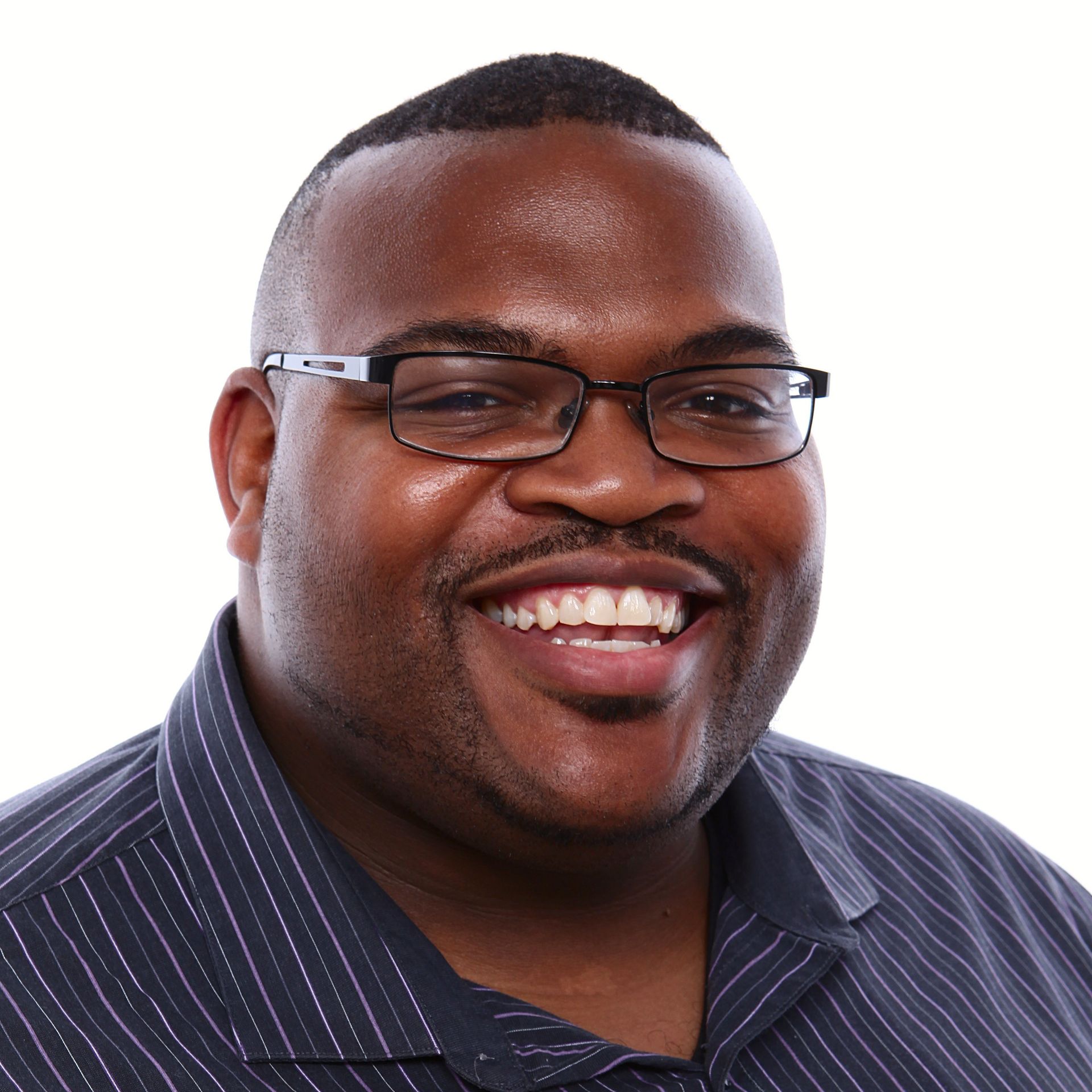 A man wearing glasses and a striped shirt smiles for the camera