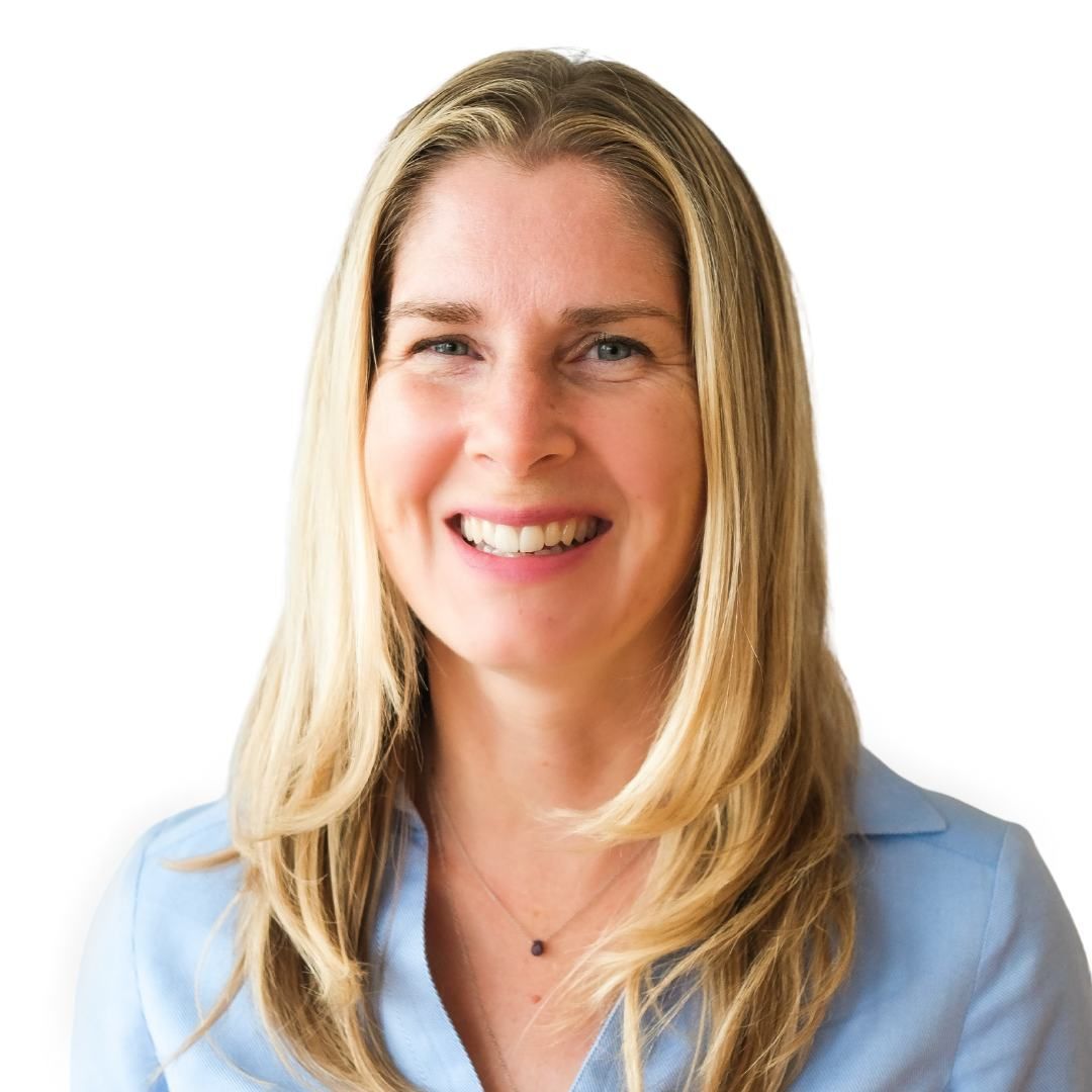 A woman wearing a blue shirt and a necklace smiles for the camera