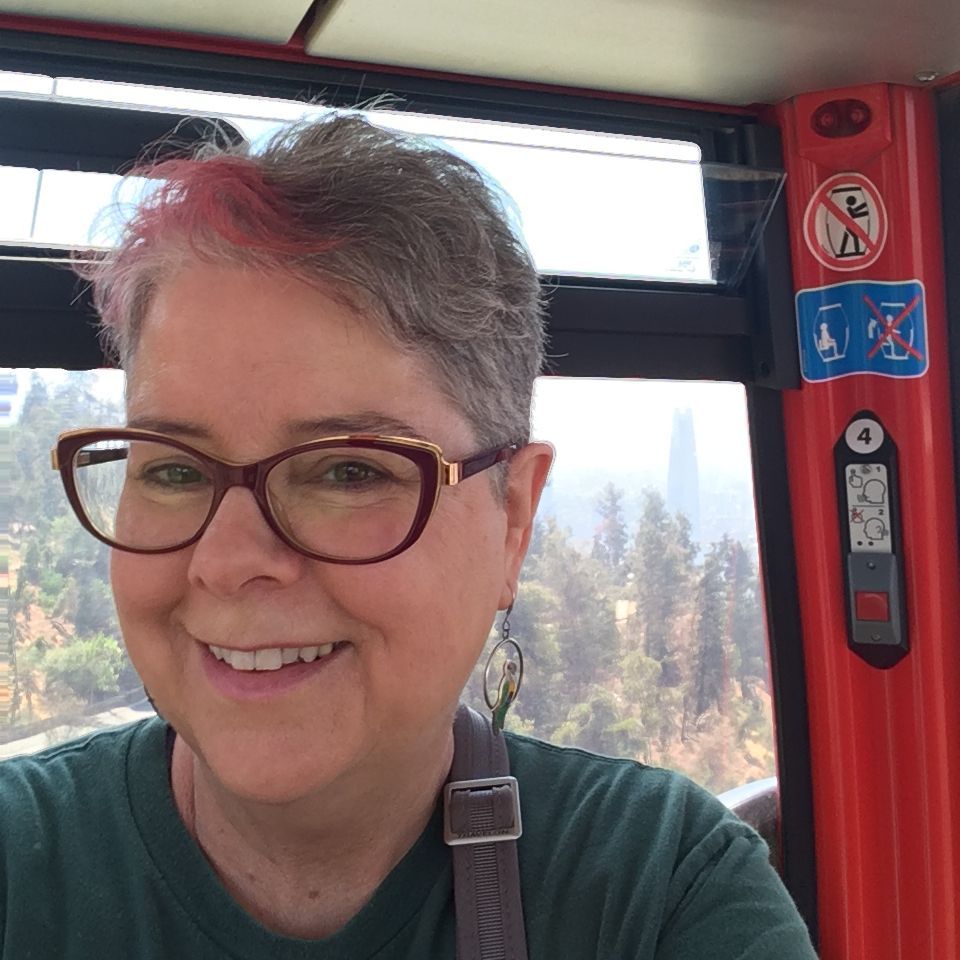 A woman wearing glasses and a green shirt is smiling