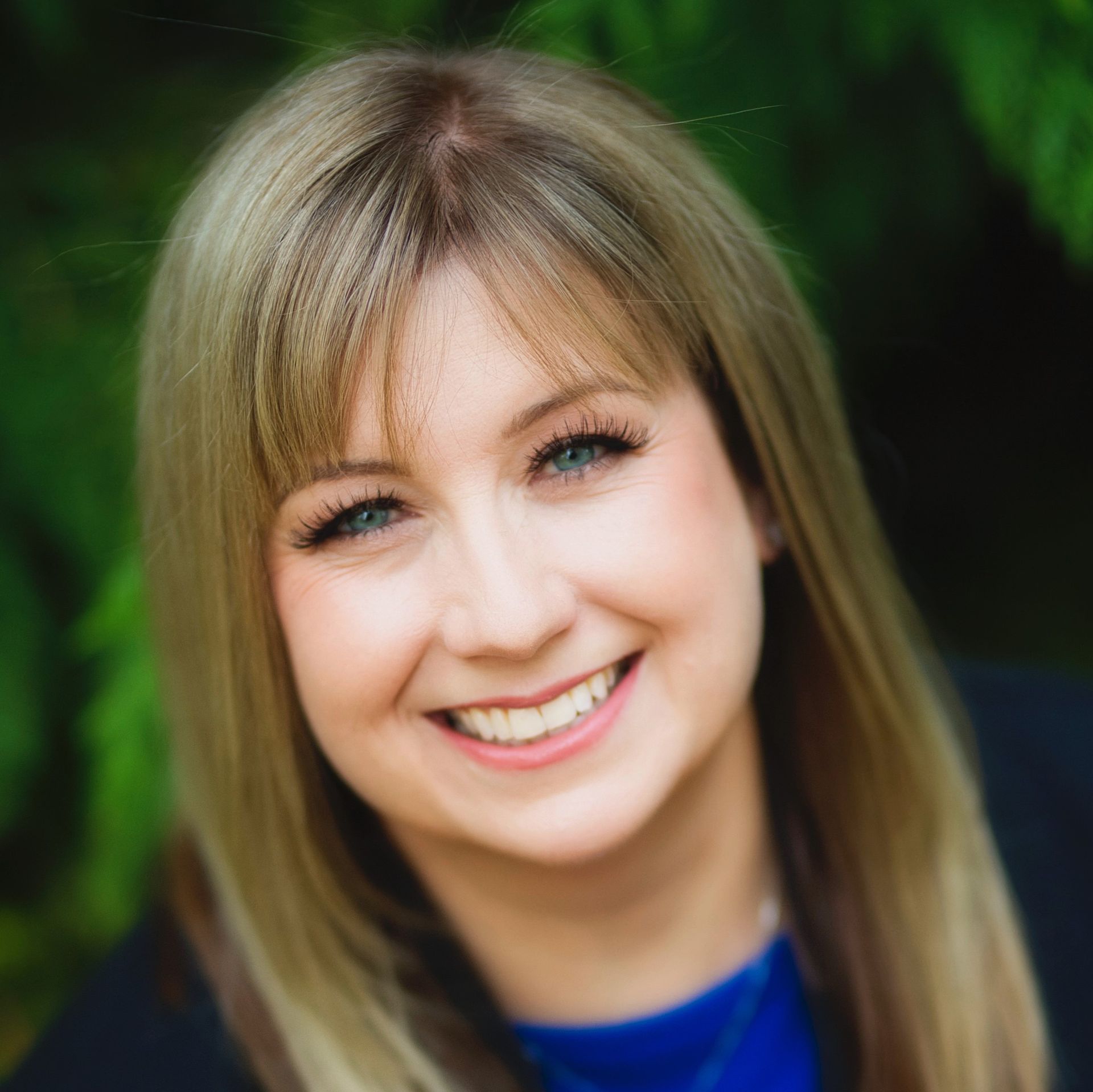 A woman with blonde hair and blue eyes is smiling for the camera.