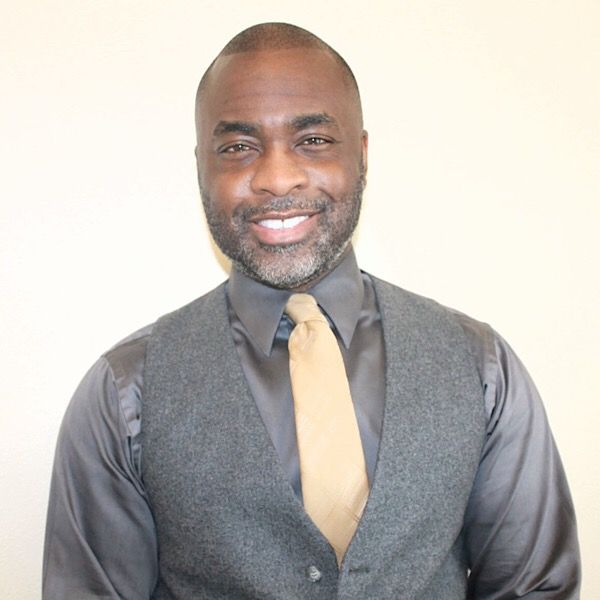 A man wearing a vest and tie is smiling for the camera