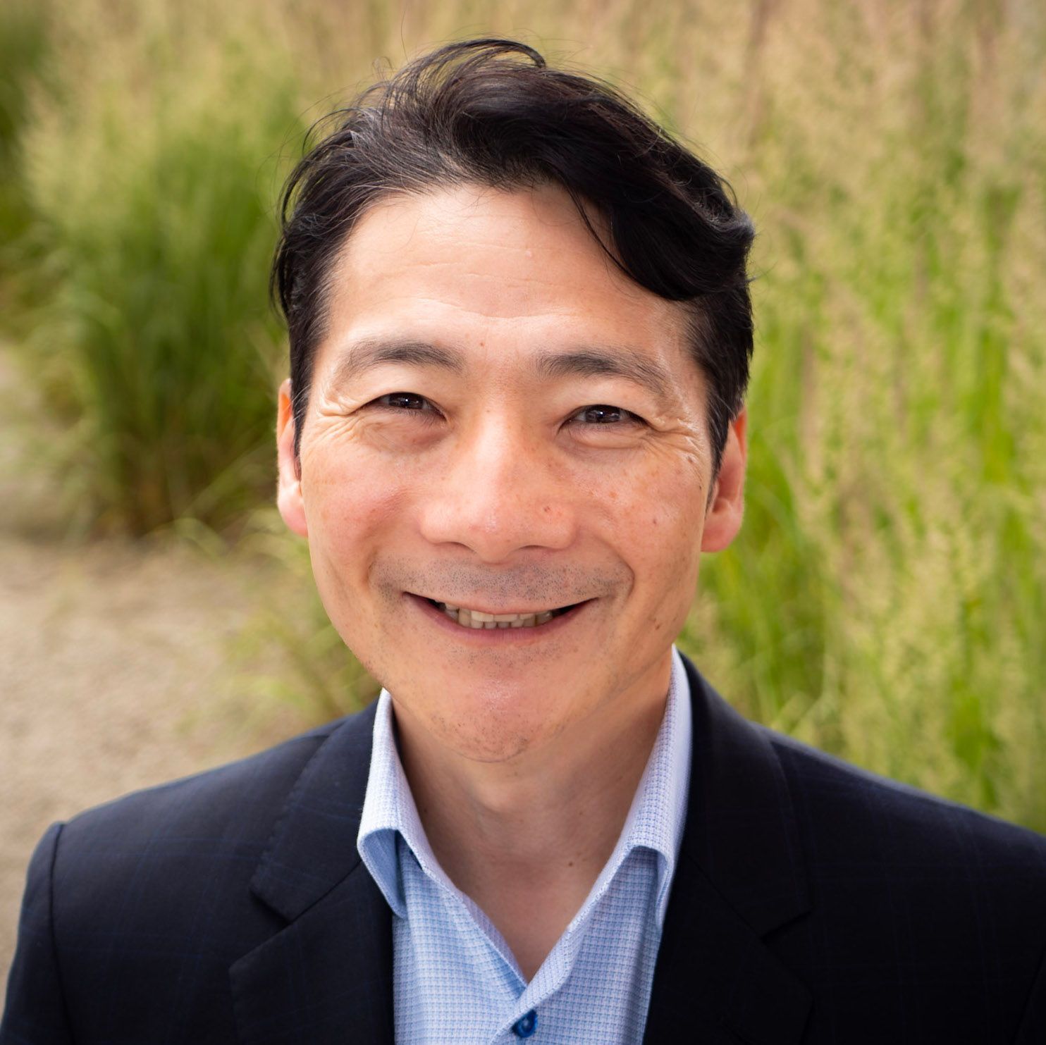 A man in a suit and blue shirt is smiling for the camera.