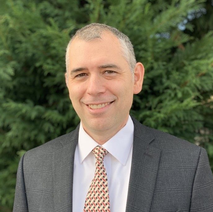 A man in a suit and tie is smiling for the camera.