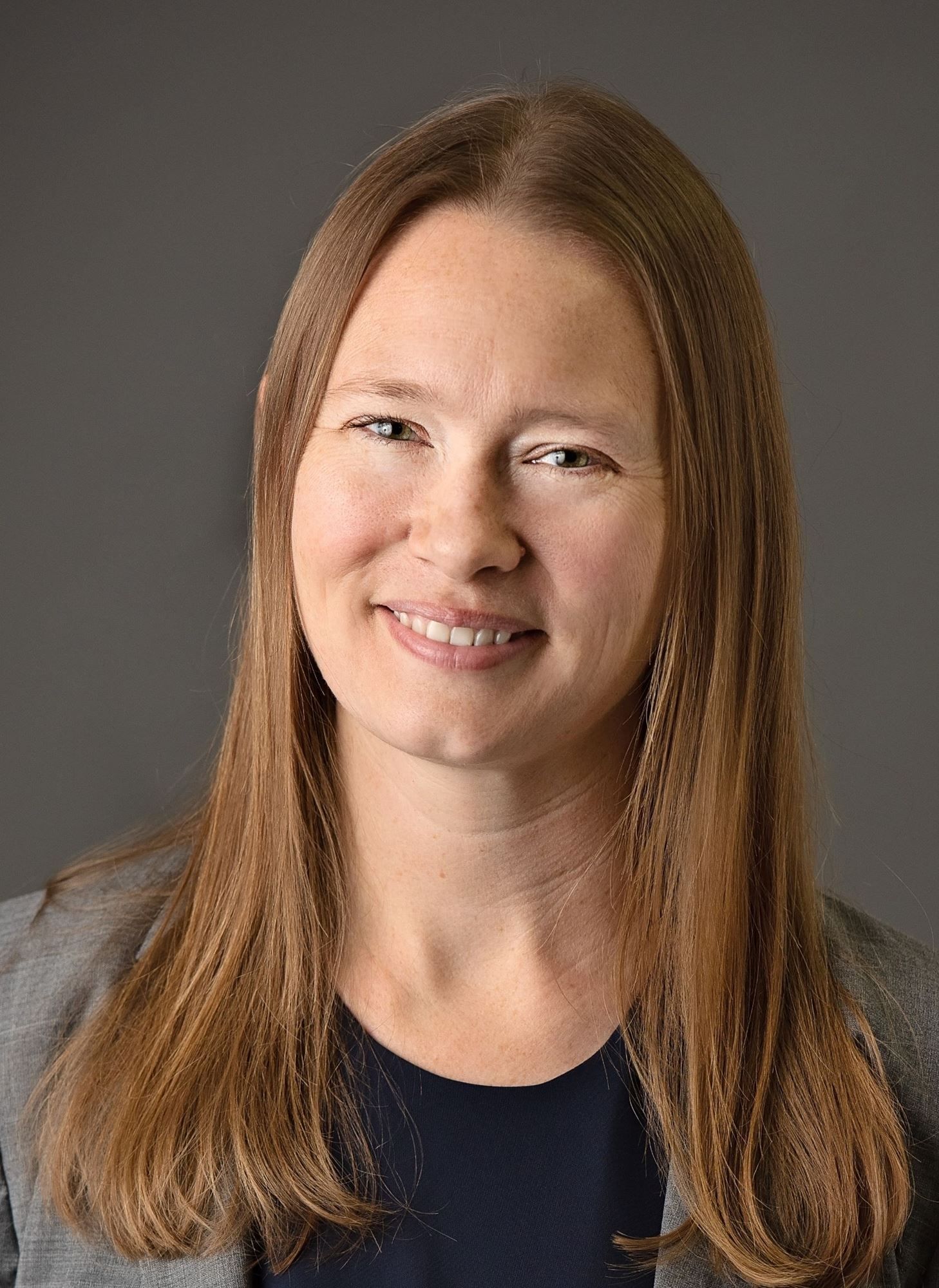 A woman with long brown hair is smiling for the camera