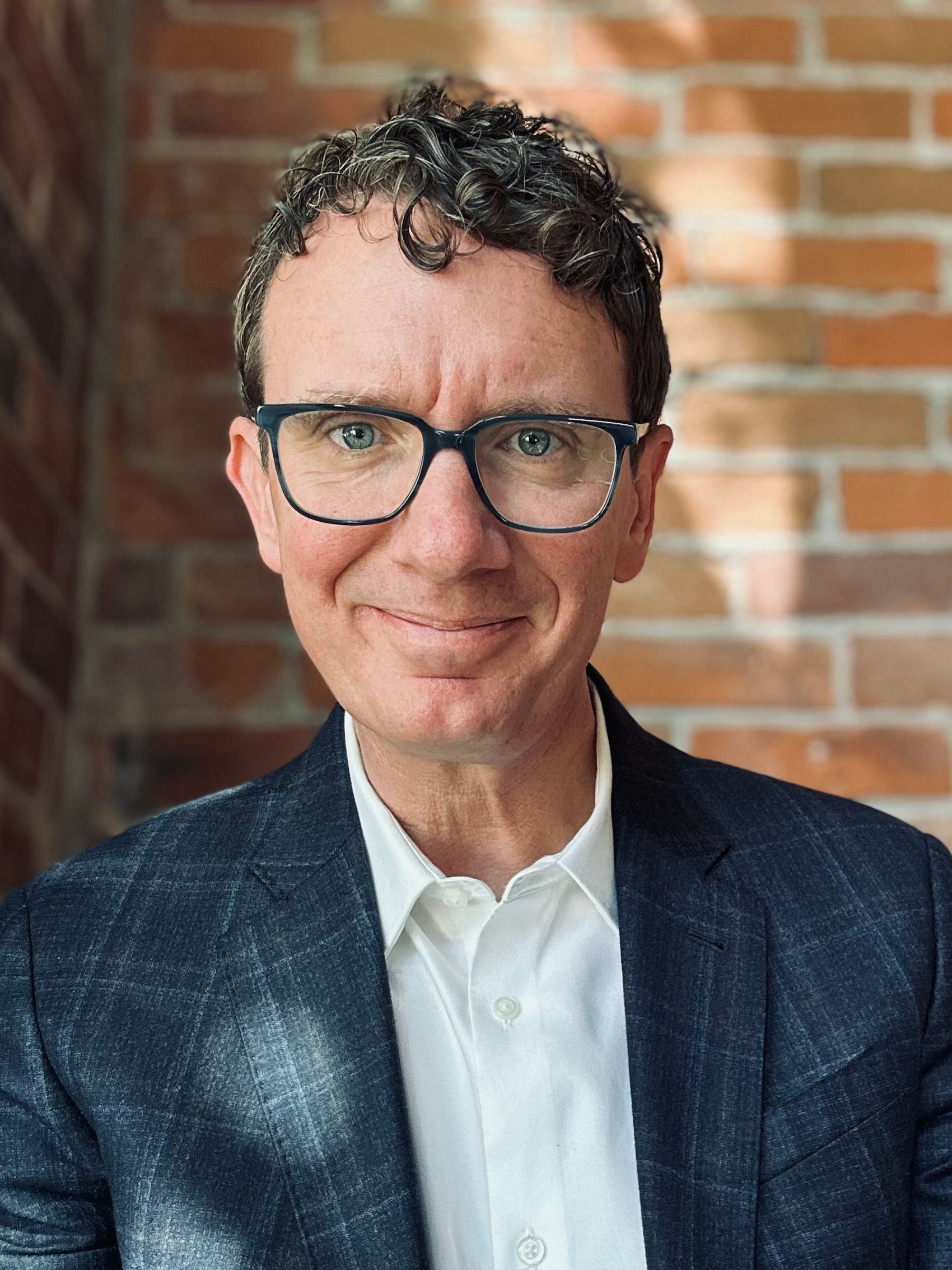 A woman with long curly hair wearing a gold necklace