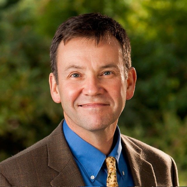 A man in a suit and blue shirt is smiling for the camera.