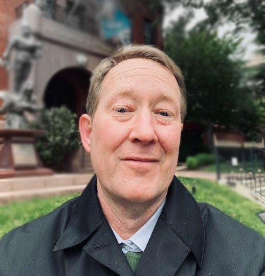 A man standing outside wearing a suit.