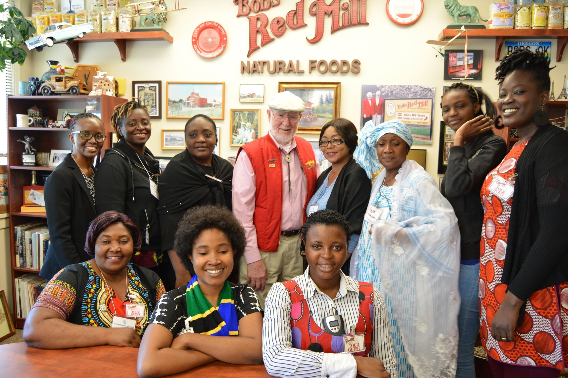 A group of people are posing for a picture in front of a red hill natural foods store.