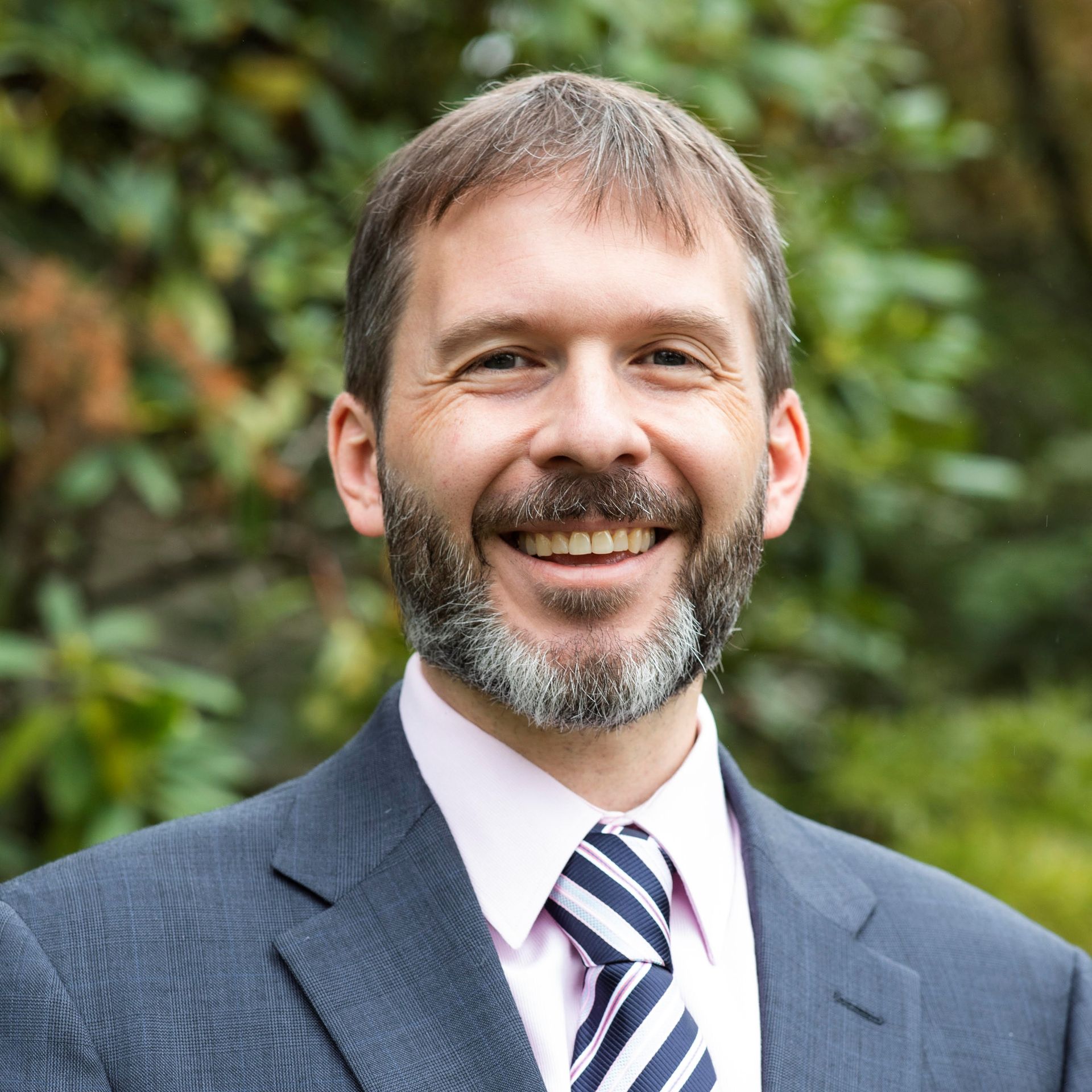 A man in a suit and tie is smiling for the camera.