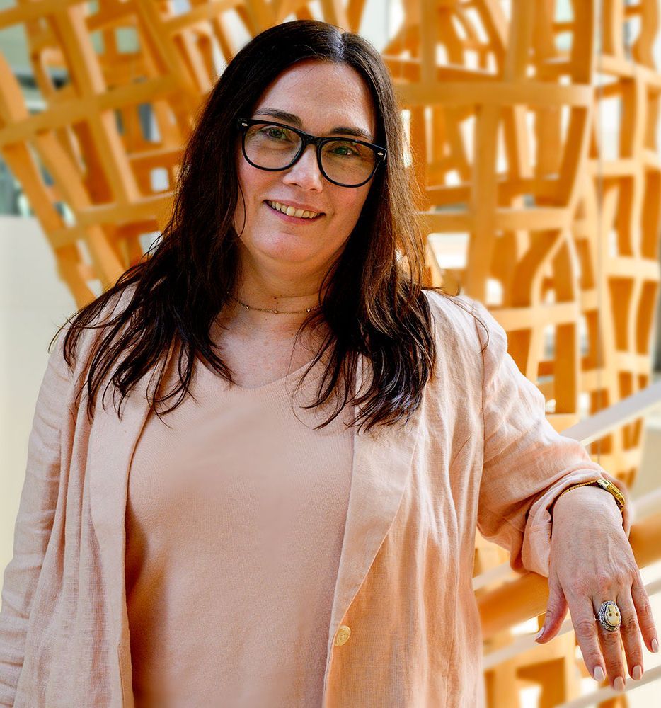 A woman with blonde hair is wearing a green sweater and a blue shirt