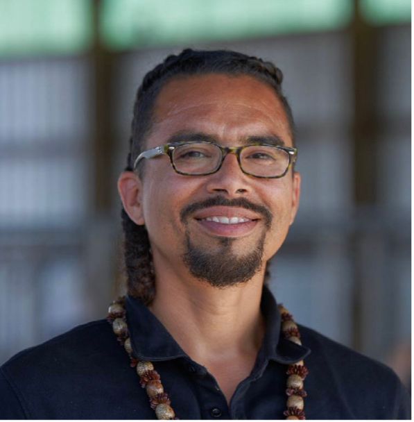 A man wearing glasses and a striped shirt is smiling for the camera.