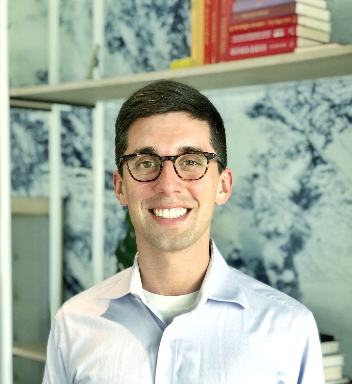 A man wearing glasses and a striped shirt is smiling for the camera.