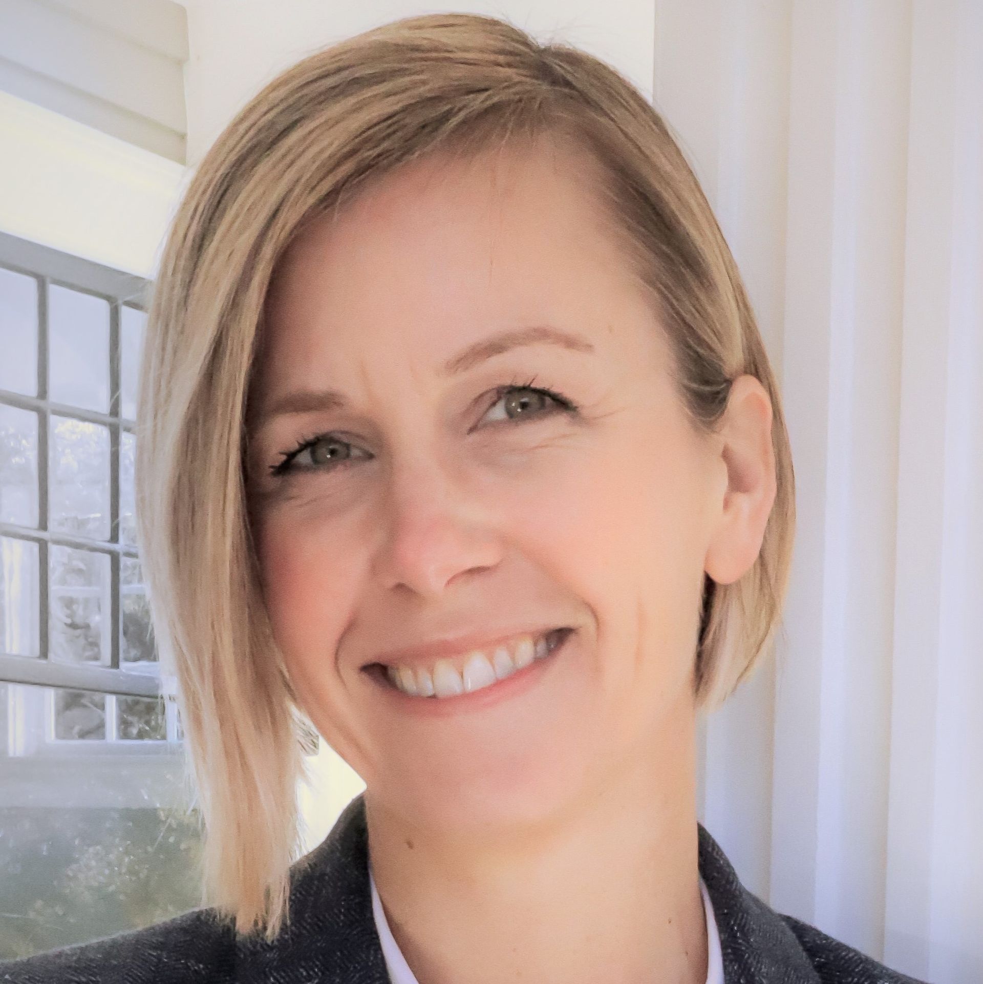 A woman with short blonde hair is smiling for the camera.