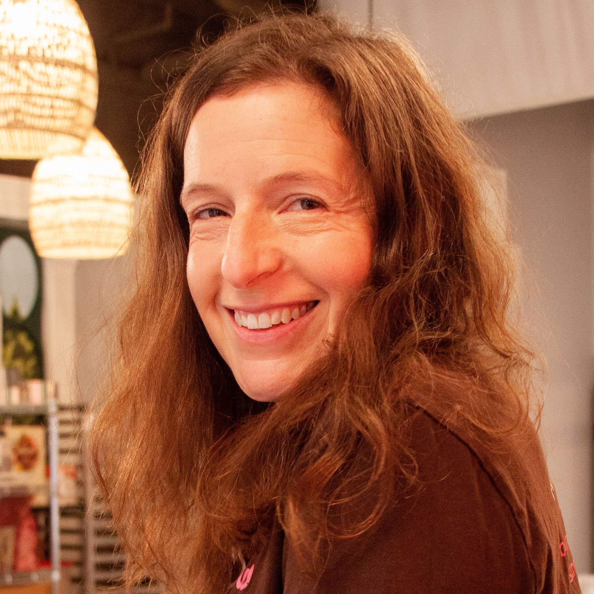 A woman with long brown hair is smiling for the camera