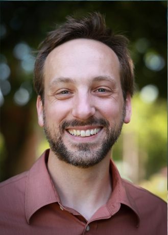 A woman wearing glasses and a green shirt is smiling
