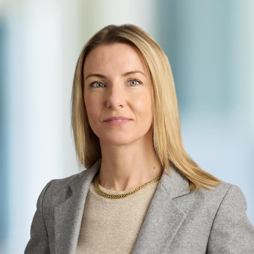 A woman with blonde hair is wearing a green sweater and a blue shirt