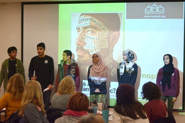 A group of people are standing in front of a large screen.