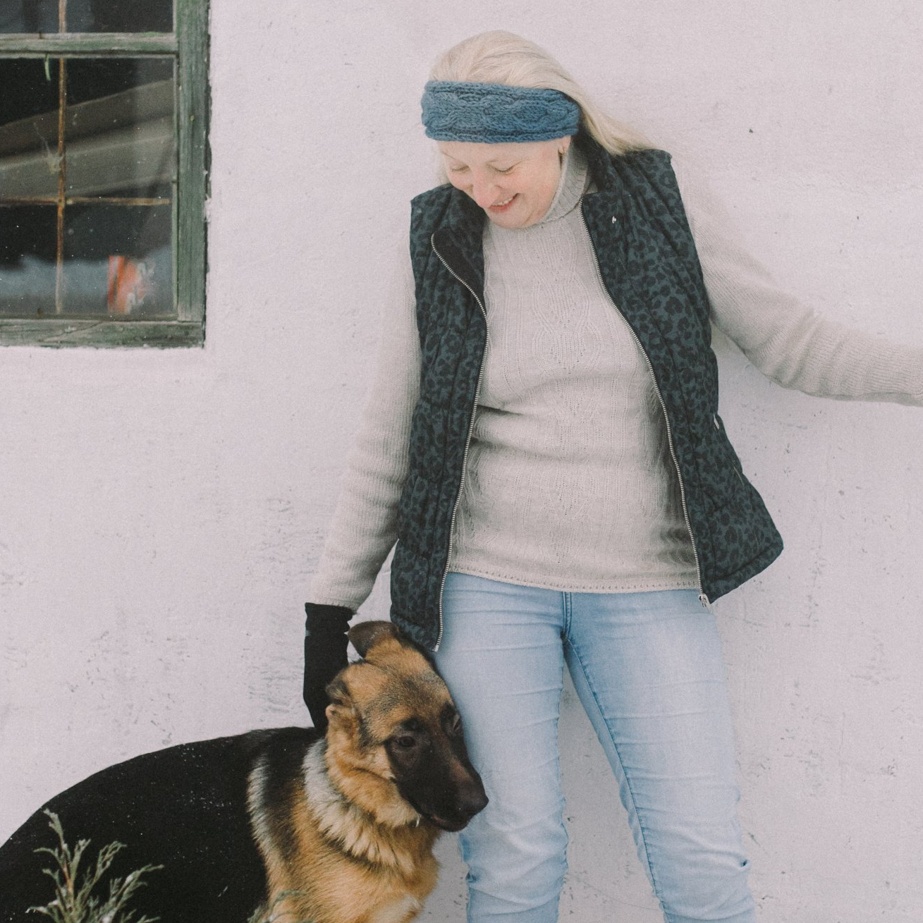 A woman standing next to a german shepherd wearing a headband