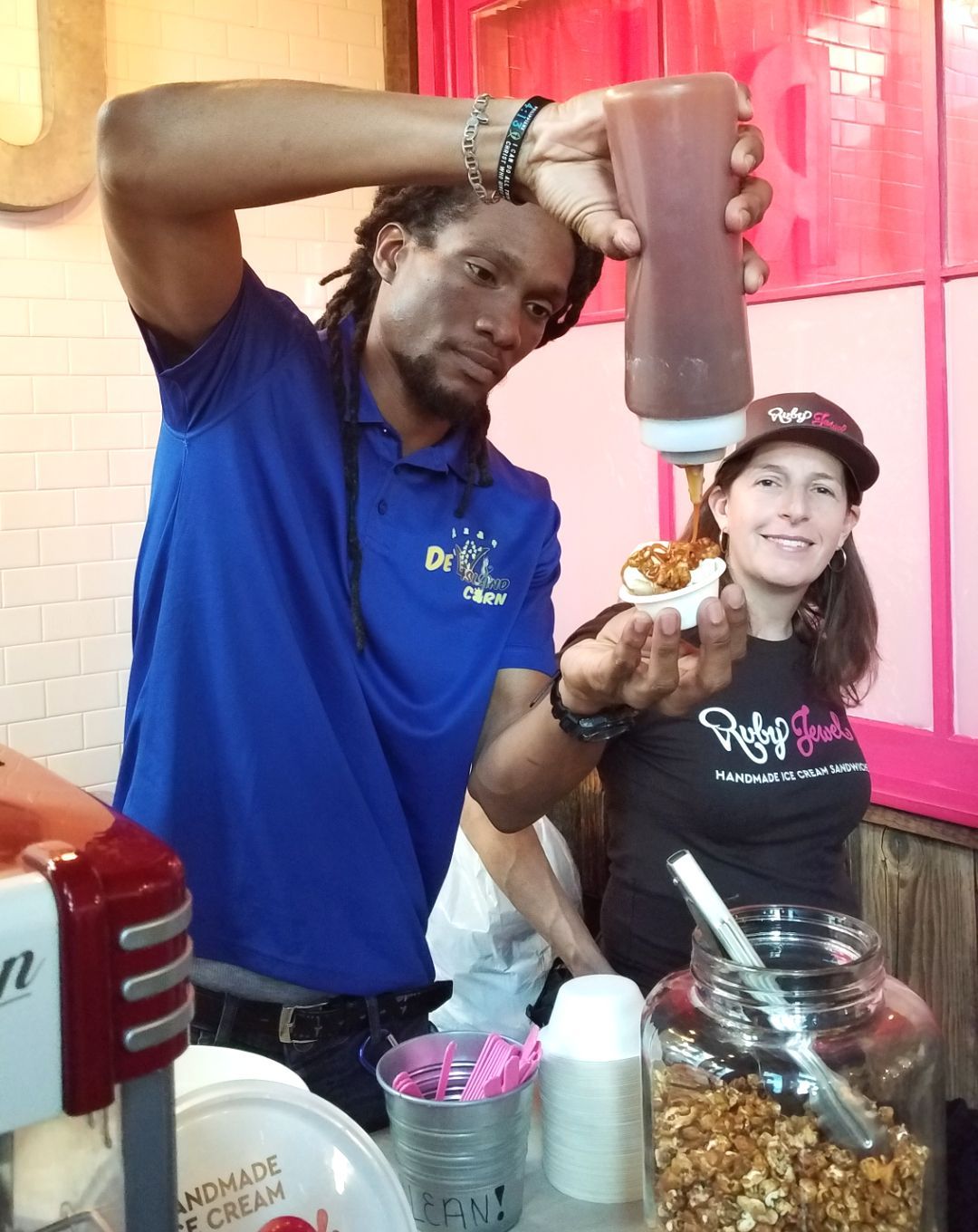 A man in a blue shirt is pouring sauce into a woman 's hand