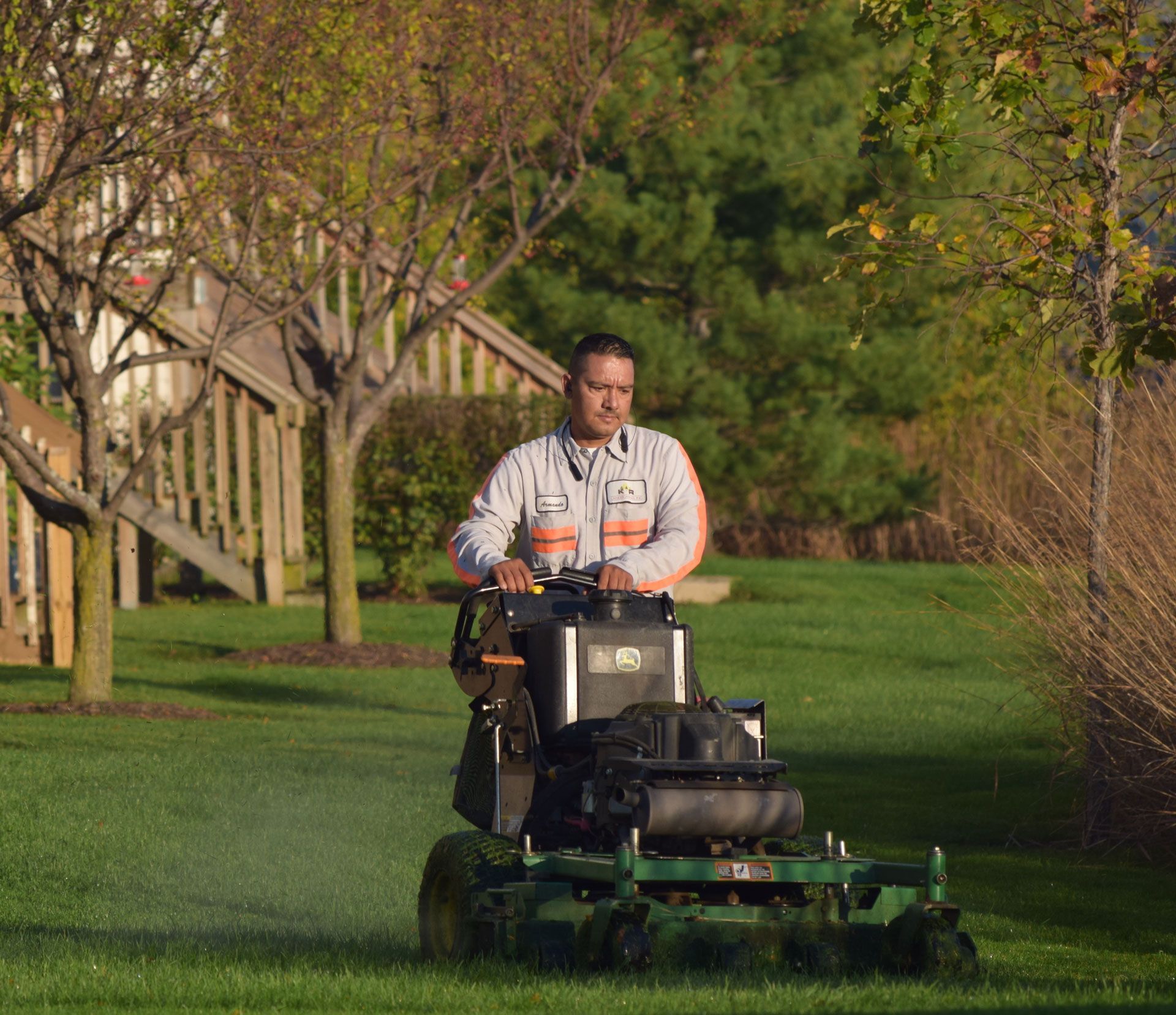 A man is riding a lawn mower on a lush green lawn.