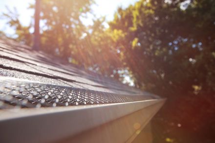 A close up of a gutter on a roof with water drops on it.