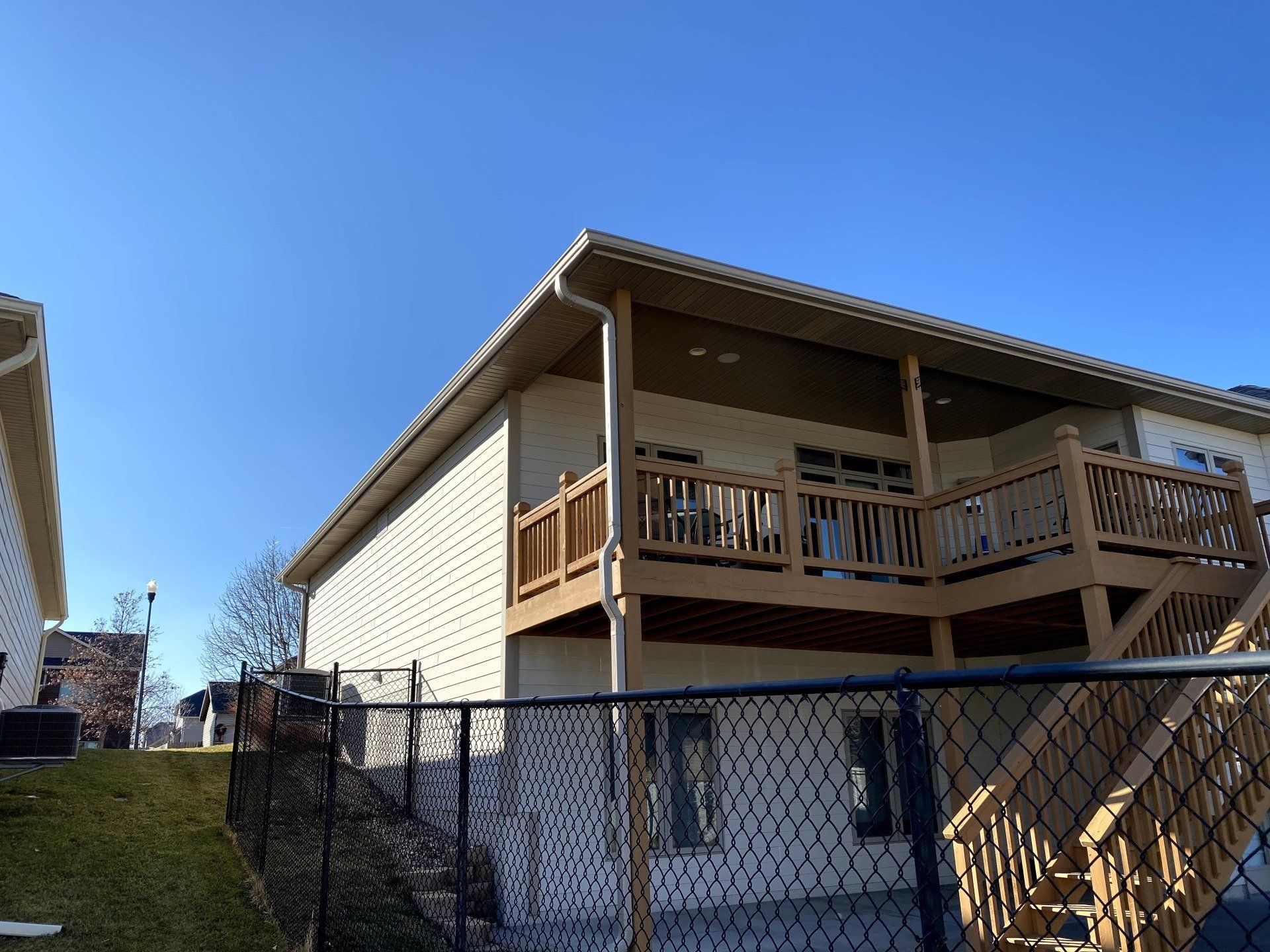 A house with a large deck and stairs behind a chain link fence