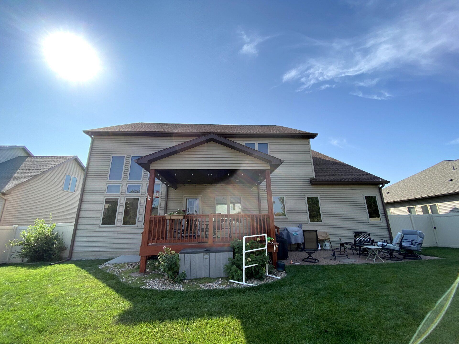 The back of a house with a deck and a hot tub in the backyard.